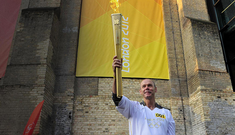 Clive holding the olympic torch in the air.