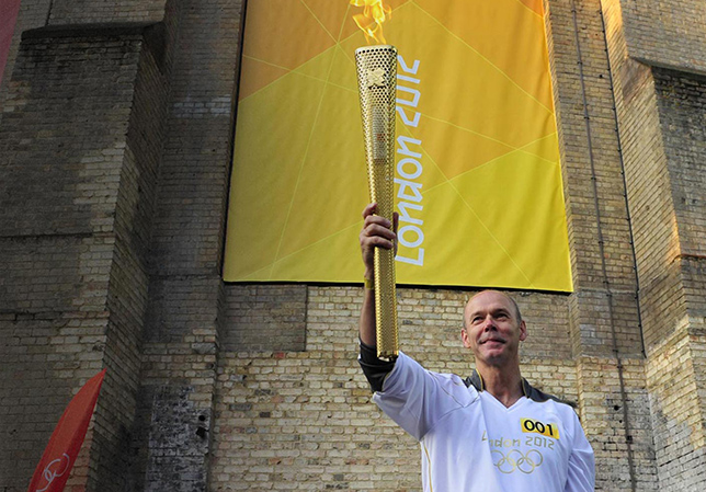 Clive holding the olympic torch in the air.